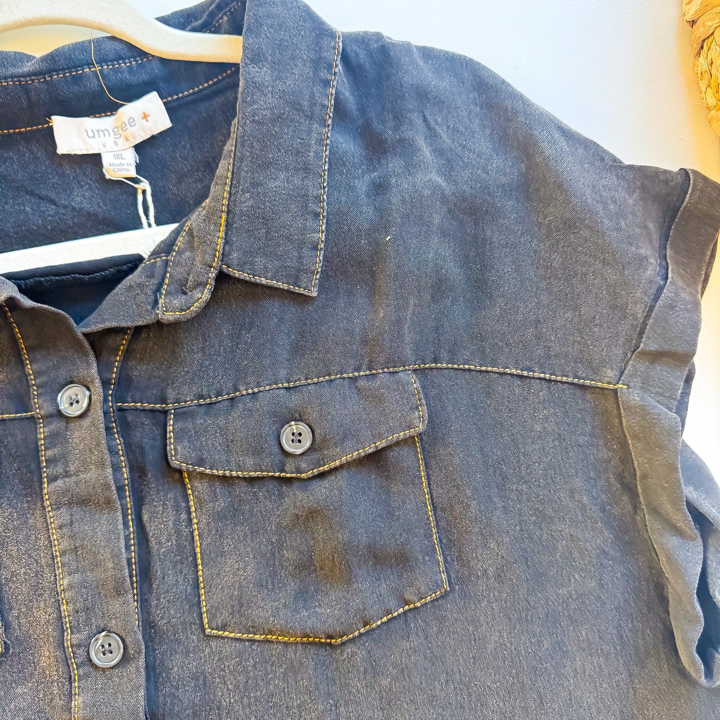 Close-up of golden topstitched chest pocket on washed black Umgee plus dress