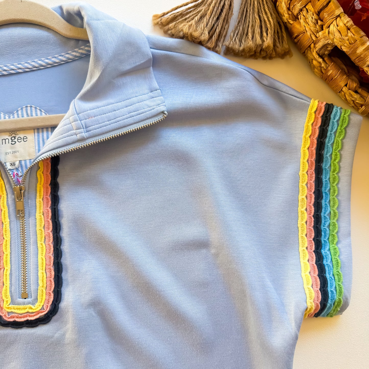 Close-up of rainbow scalloped trim on light blue zip top