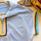 Close-up of rainbow scalloped trim on light blue zip top