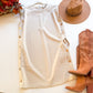 Ecru dress flat lay with gold side buttons