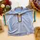 Light blue zip-neck top with rainbow scalloped trim, flat lay