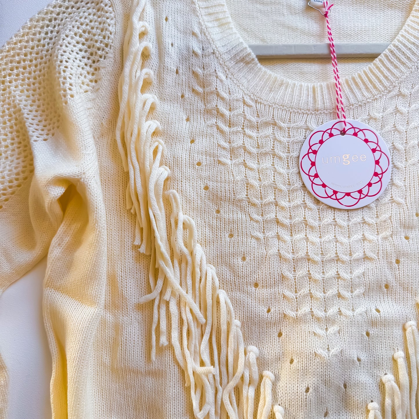 Cream fringe sweater neckline detail