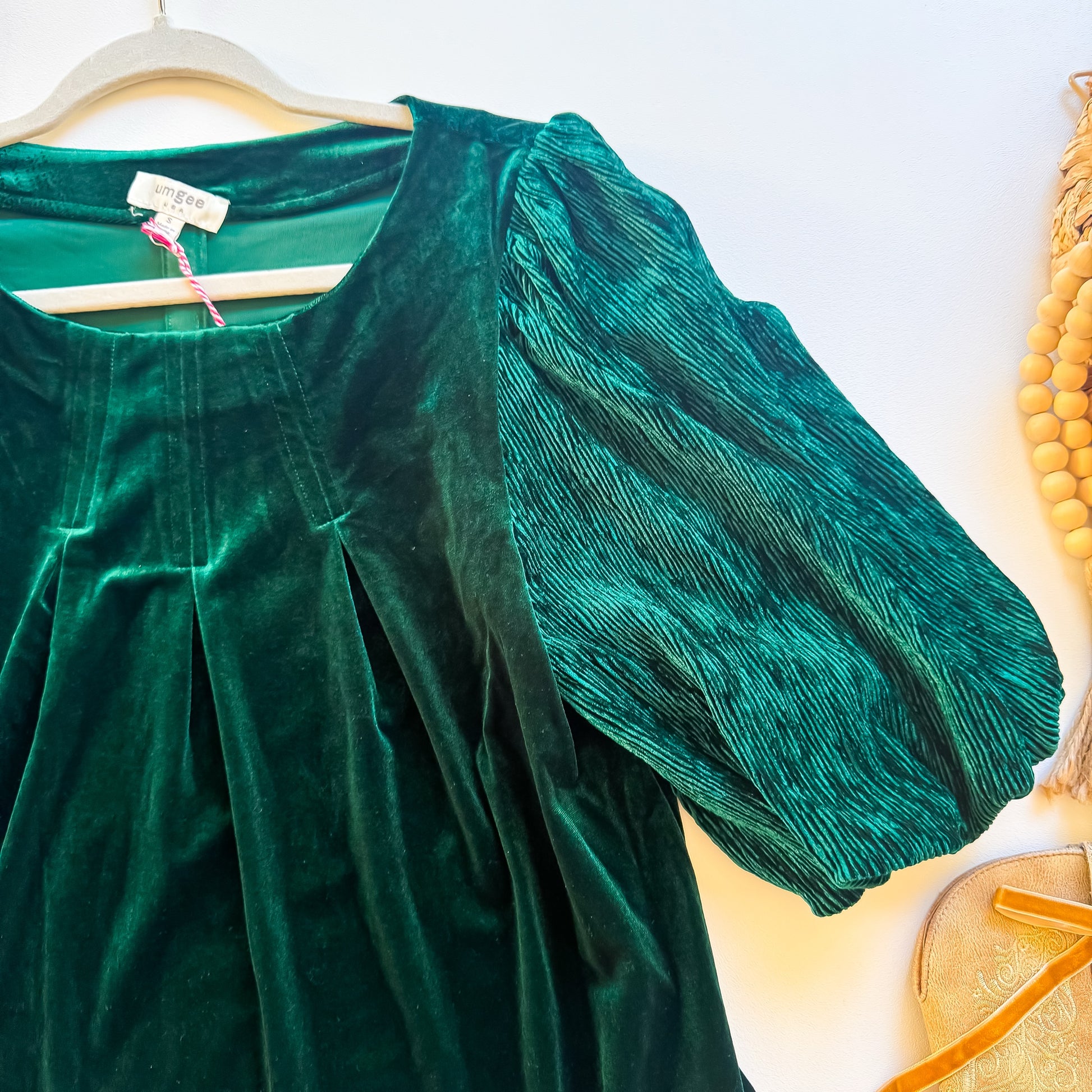 Close-up of ribbed velvet puff sleeve and pleated scoop neckline on emerald Umgee top